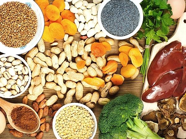 A variety of foods rich in iron are spread on a wooden surface, grouped by type in a colourful, organised layout—perfect inspiration to reduce food waste at home whilst enjoying nutritious options like peanuts, white beans, parsley, and lentils.