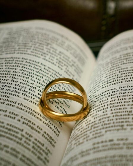 Two gold rings rest on an open Bible, forming a heart-shaped shadow—symbolising love, marriage, and the bond couples share. The lighting highlights the rings and text, capturing a moment cherished in Christian dating journeys.